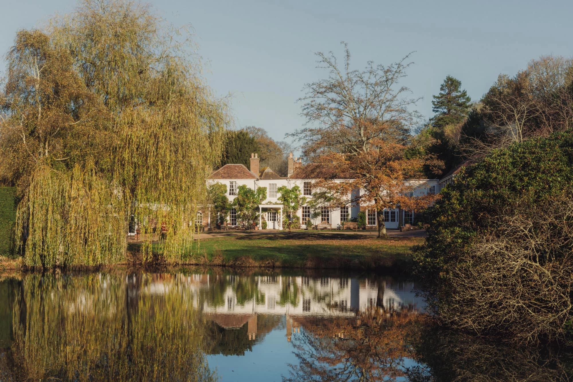 The main house at Crafted at Powdermills, seen across the private lake at golden hour
