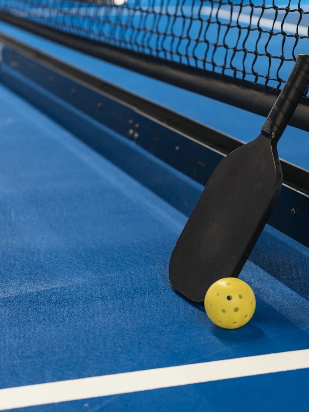 A padel racket and ball resting on court – Padel