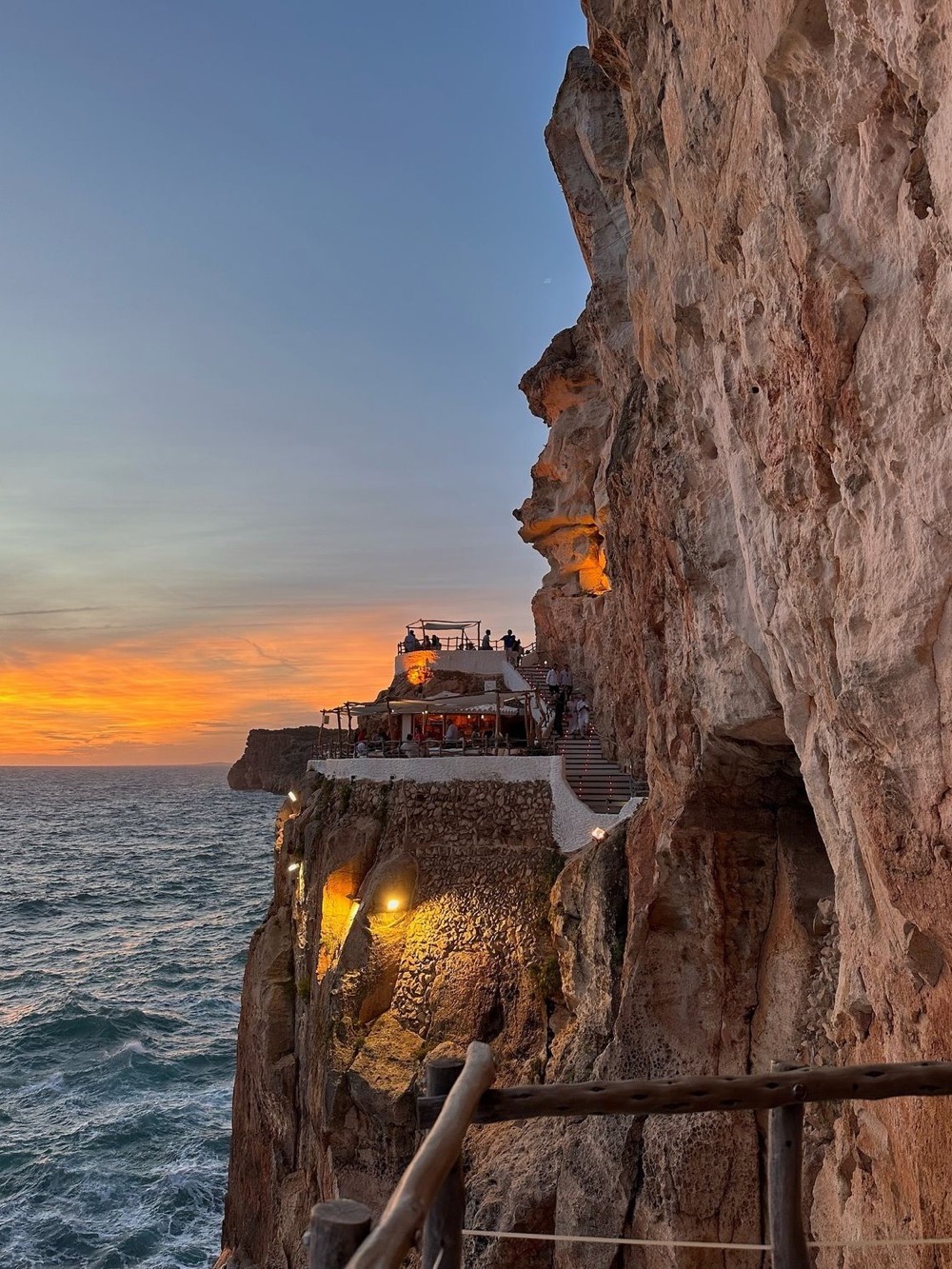 A cliffside bar glowing at sunset above the sea – Cova d’en Xoroi